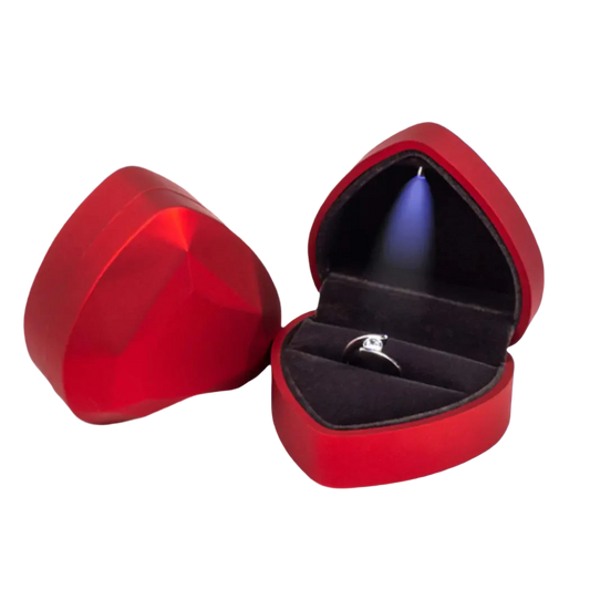 Red heart-shaped jewelry box with a ring inside on a white background