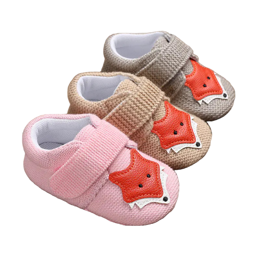 Three pairs of baby shoes with fox design on a wooden surface