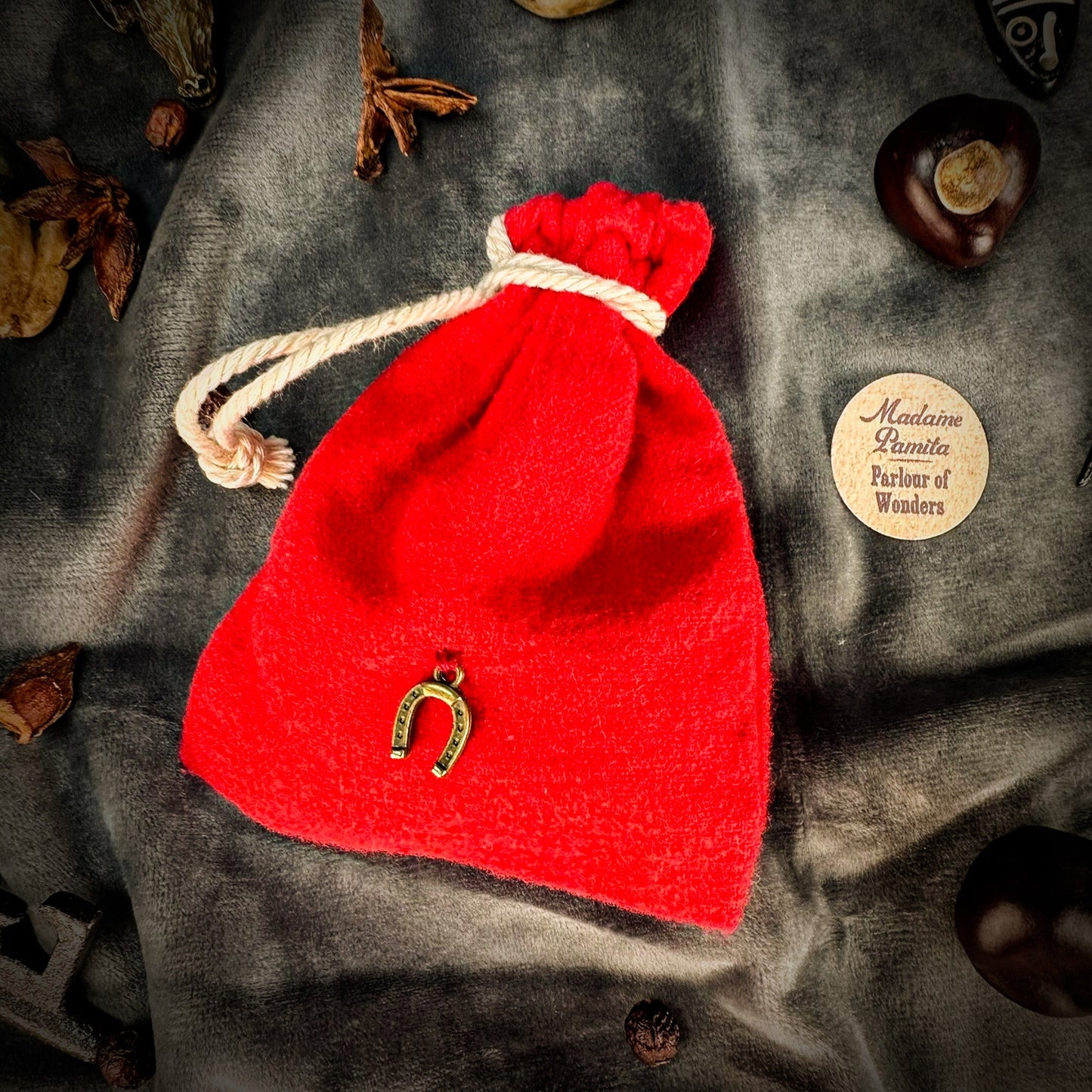 Red drawstring bag with a gold horseshoe charm on a textured surface.