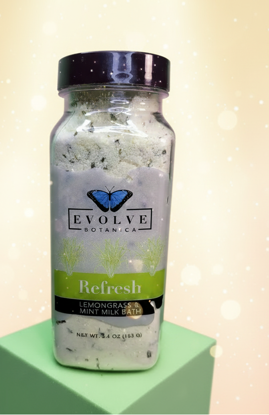 Bottle of Evolve Botanicals Lemongrass & Mint Milk Bath on a green background