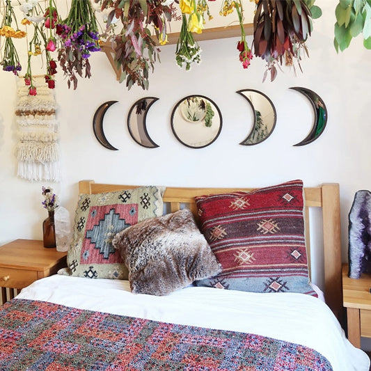 Bedroom with colorful bedding, pillows, and wall art featuring moon phases.