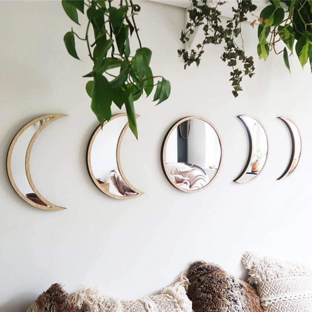 Set of five crescent moon-shaped mirrors on a wall with plants and a textured rug.
