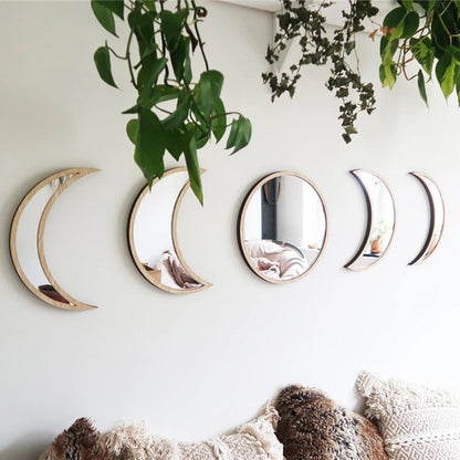 Set of five crescent moon-shaped mirrors on a wall with plants and a textured rug.