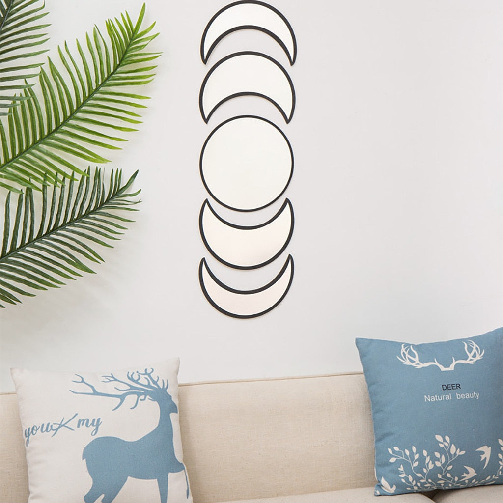 Decorative pillows with deer design on a sofa, wall art with moon phases, and green leaves.