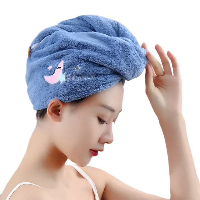Woman wearing a blue hair towel with a cartoon design, holding a white object.