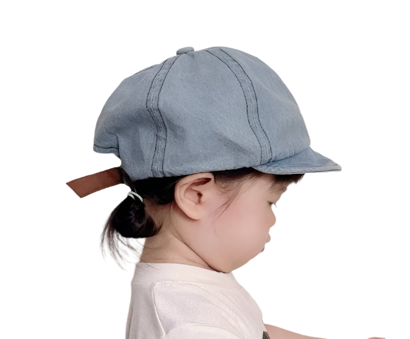 Child wearing a denim cap against a plain background