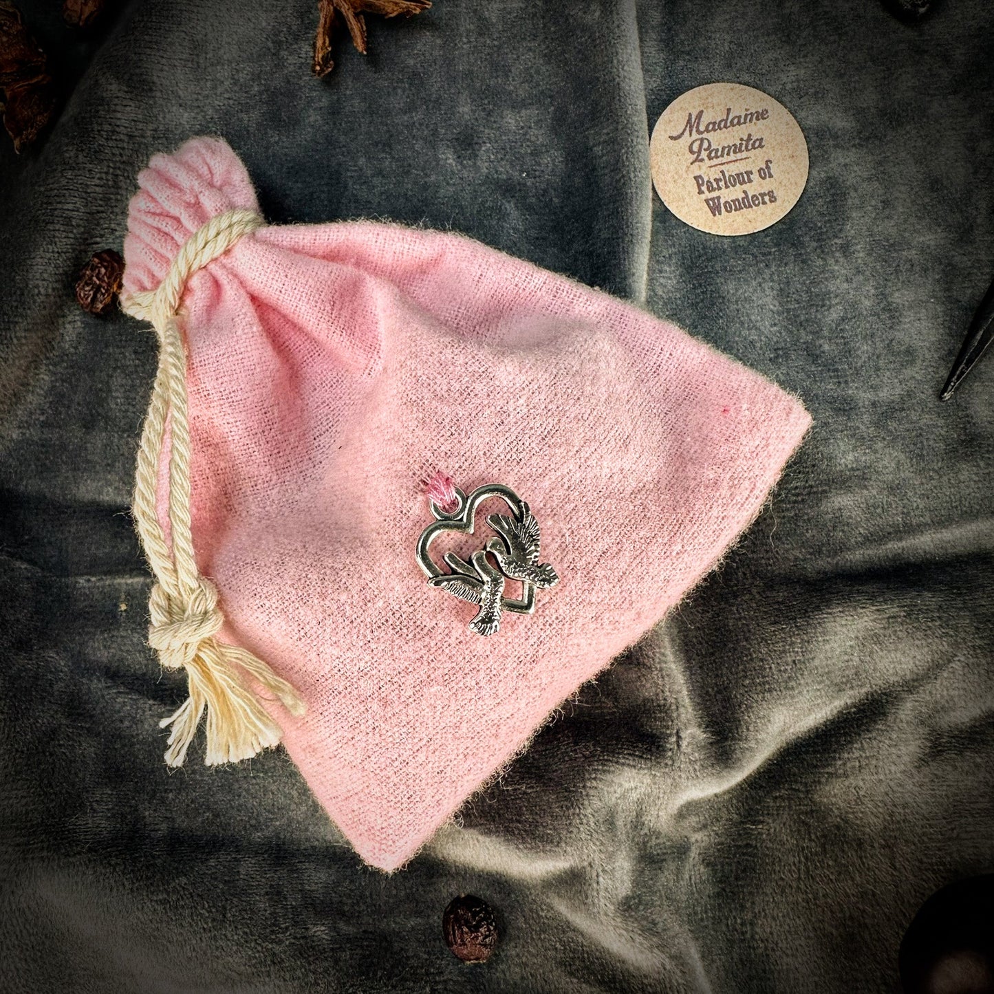 Pink drawstring bag with a decorative pin on a textured surface