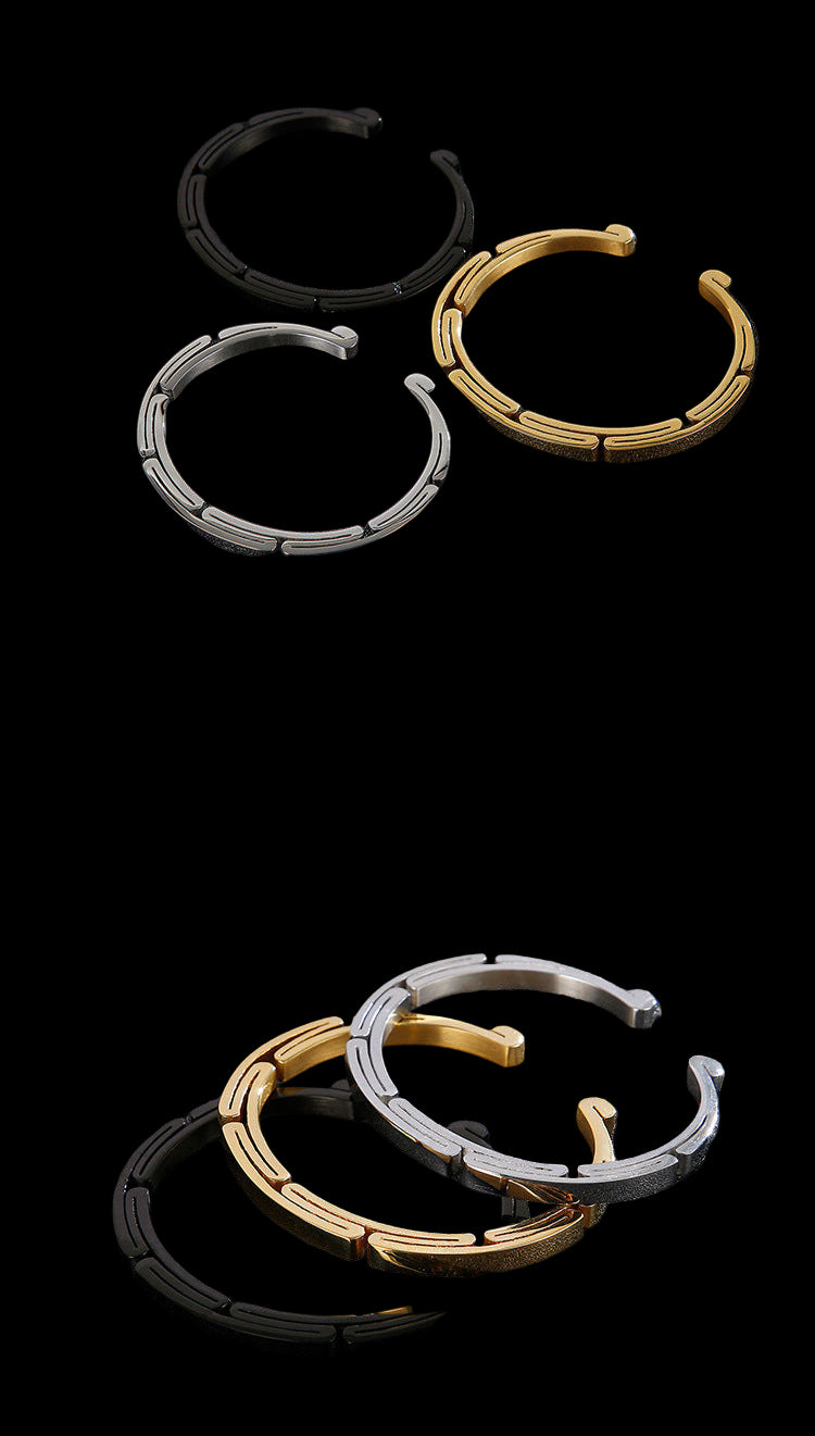 Three hoop earrings in gold, silver, and black on a dark textured surface.