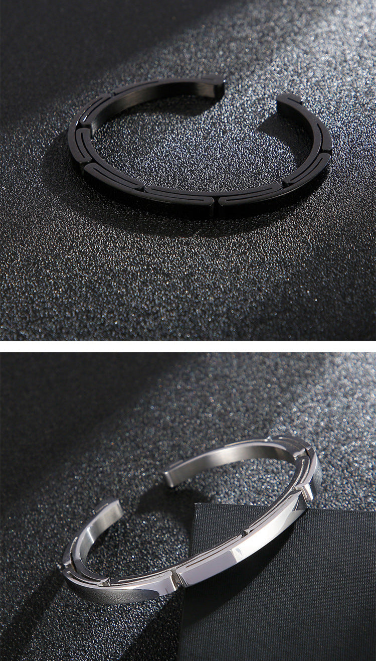 Two metallic rings, one black and one silver, on a dark textured surface.