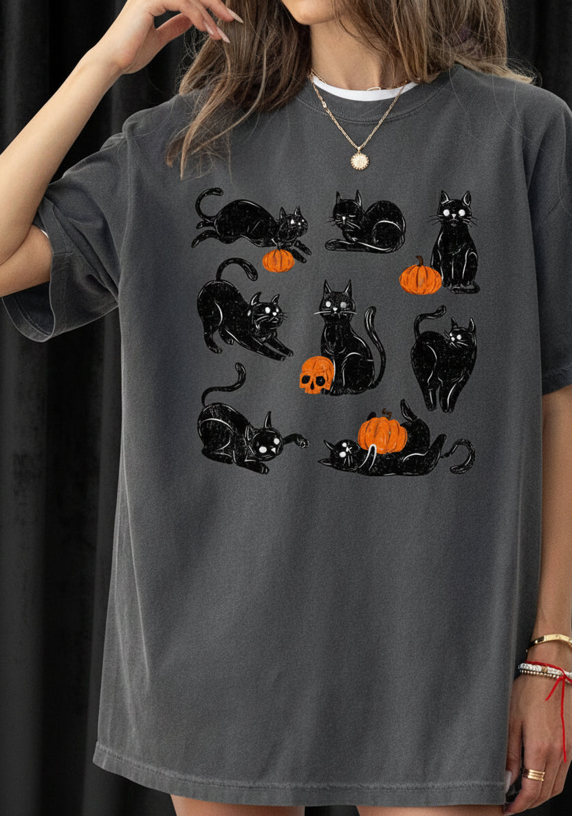 Person wearing a dark gray t-shirt with black cat and orange pumpkin designs.