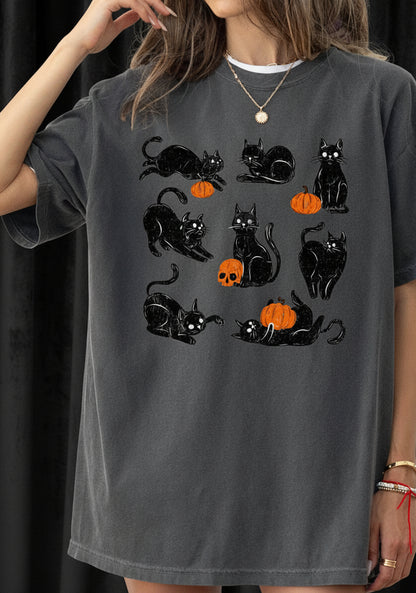 Person wearing a dark gray t-shirt with black cat and orange pumpkin designs.