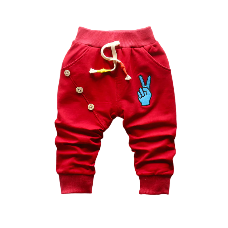 Red children's pants with a blue peace sign design on a woven mat