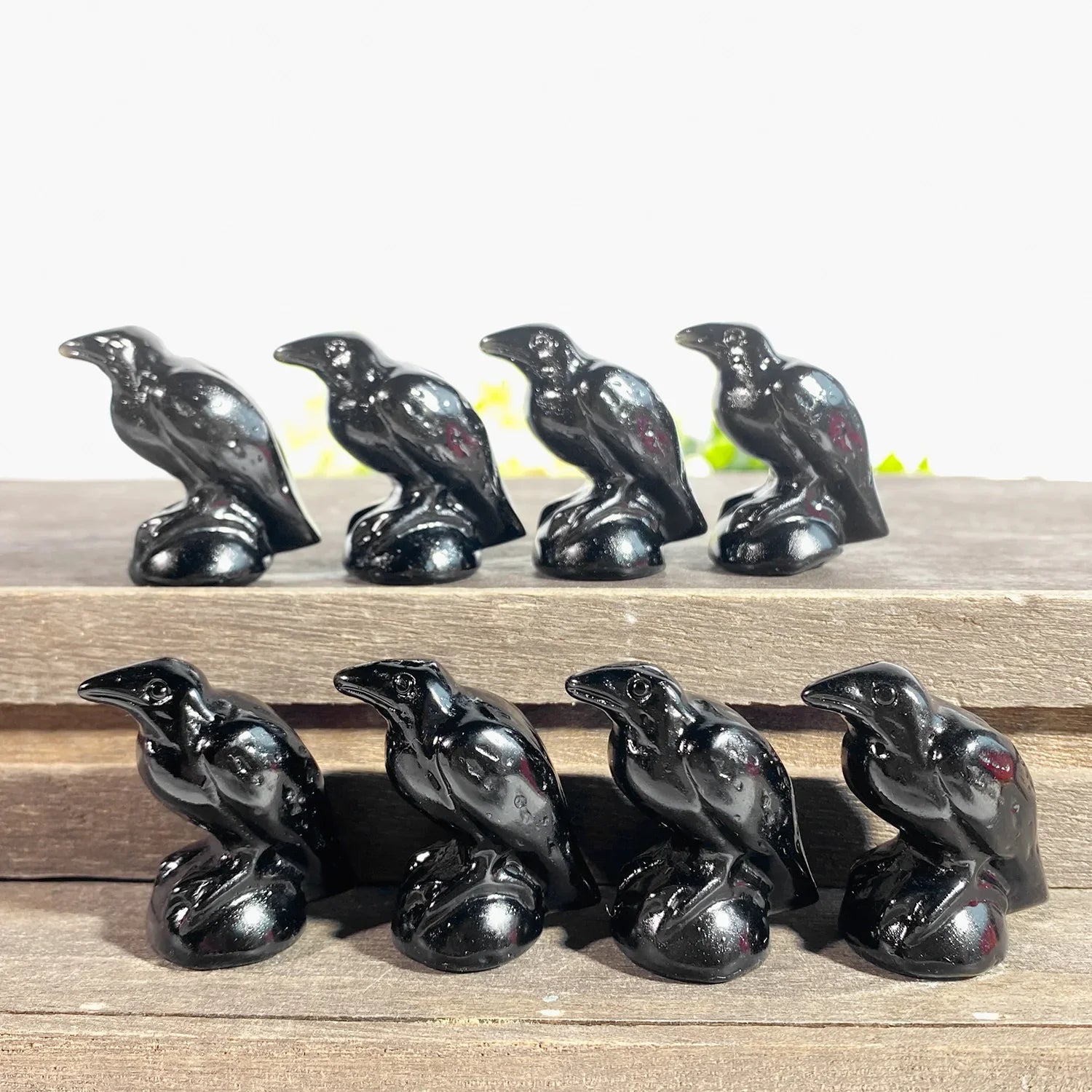 Set of black ceramic crow figurines on a wooden surface