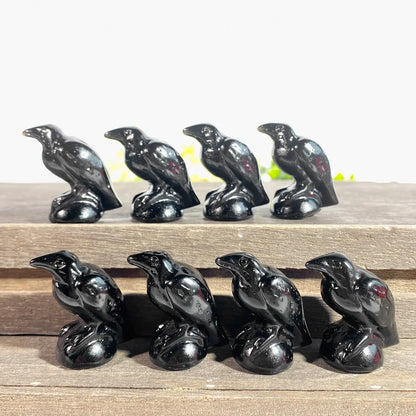 Set of black ceramic crow figurines on a wooden surface