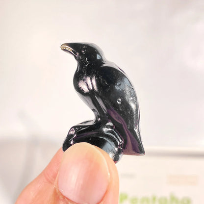Black penguin figurine held between fingers against a neutral background