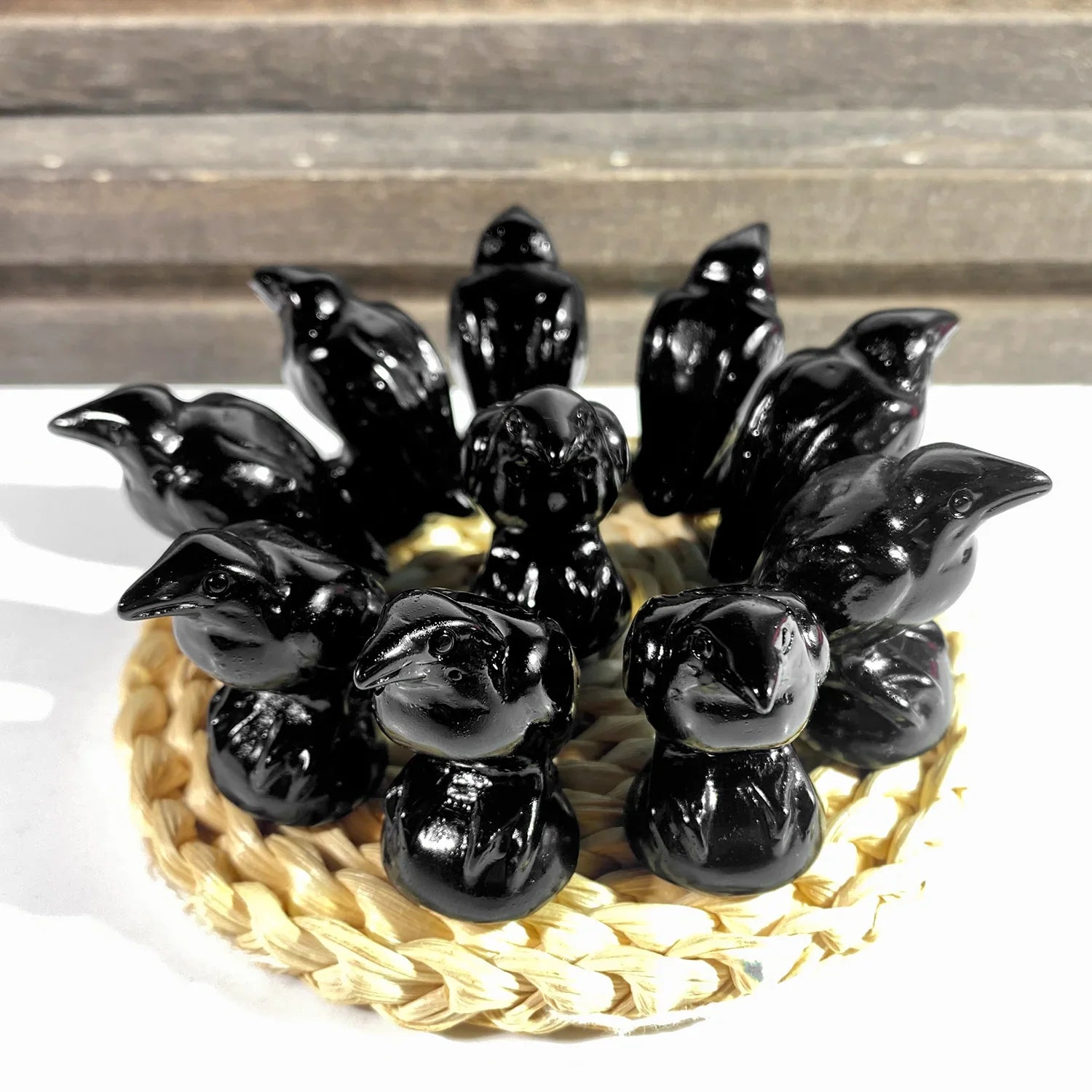 Black ceramic birds arranged in a circular pattern on a woven mat with a wooden background.