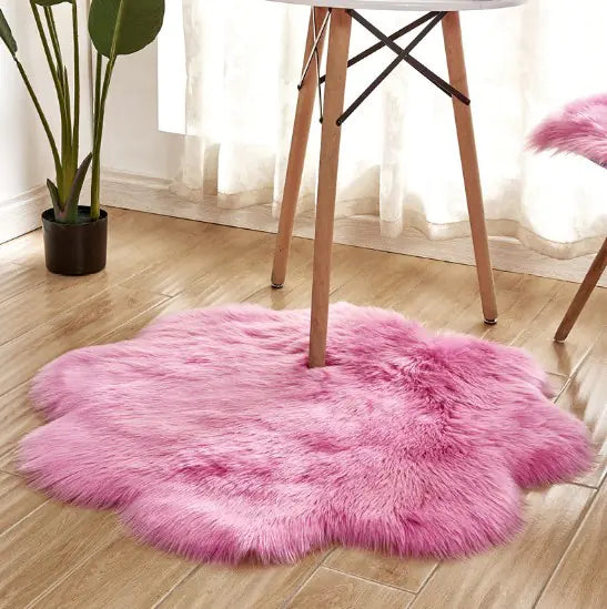 Pink fluffy rug on a wooden floor with a chair and plant in the background