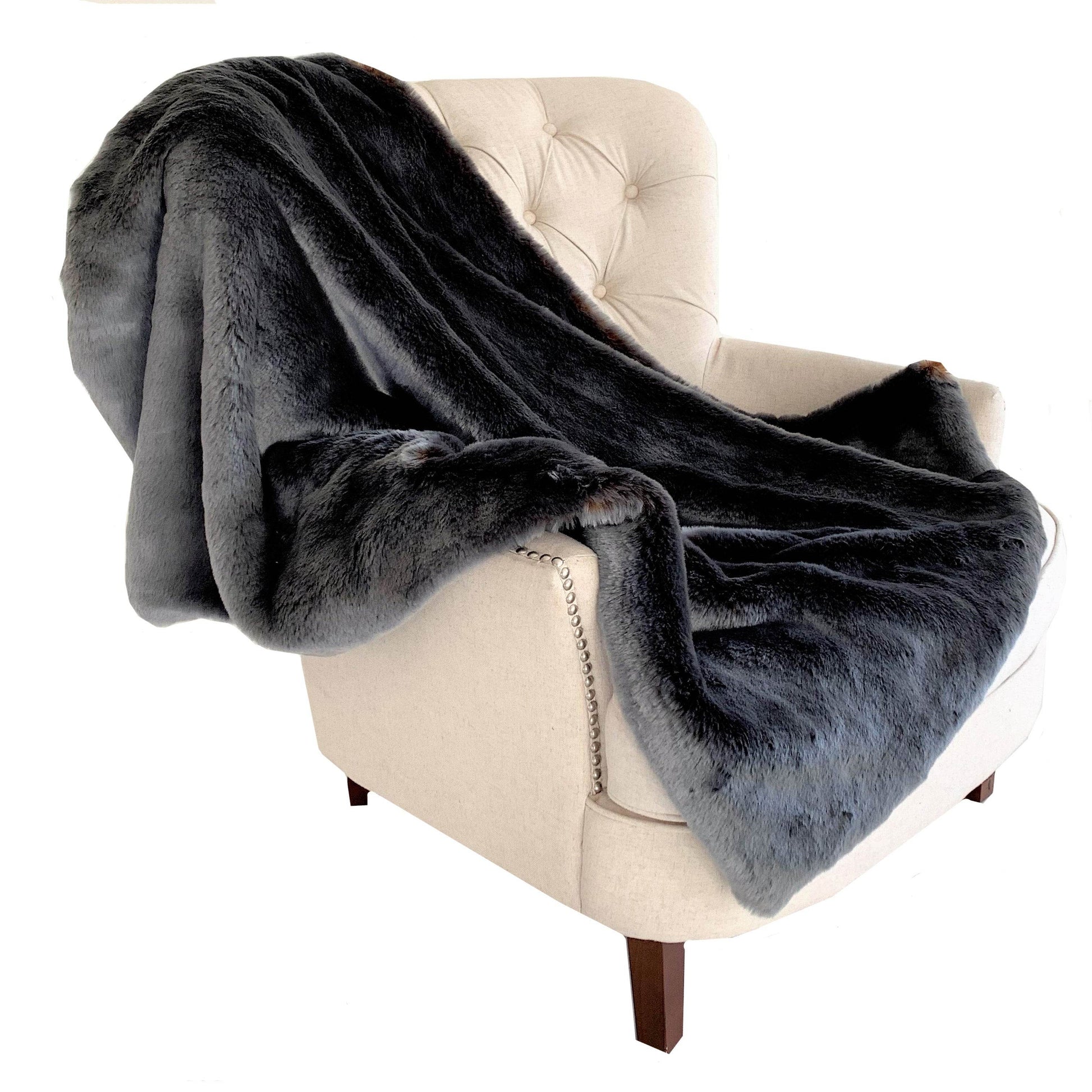 Gray plush blanket draped over a beige armchair on a white background