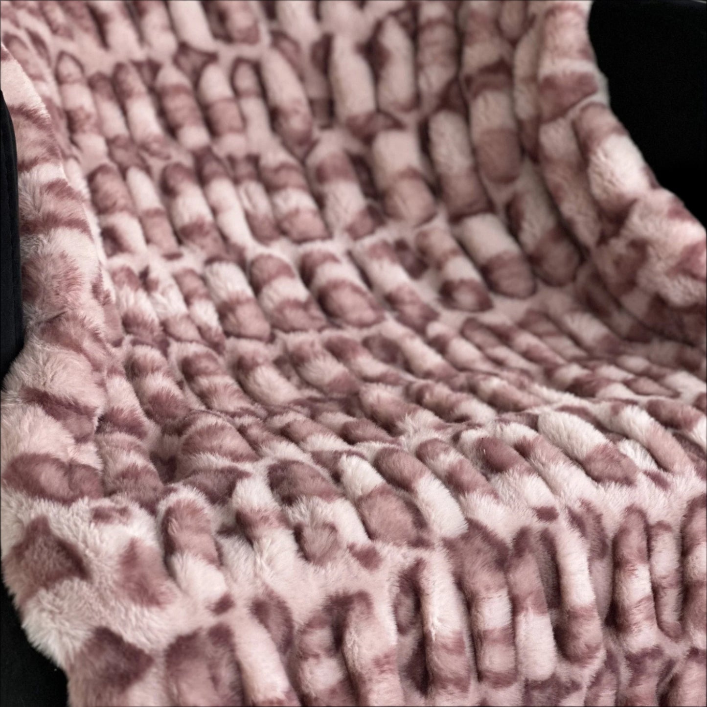 Close-up of a textured pink blanket with a grid pattern.