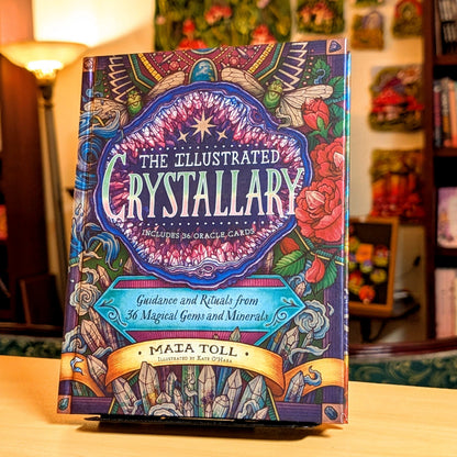 Colorful book titled 'The Illustrated Crystallary' on a wooden surface with a blurred background.