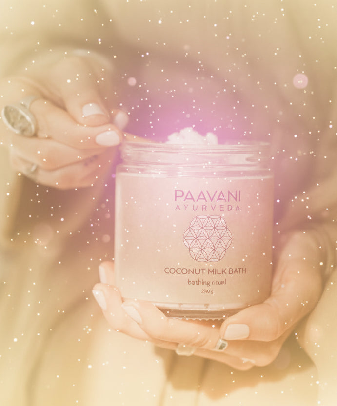 Person holding a jar of Paavani Ayurveda coconut milk bath with a spoonful of product.