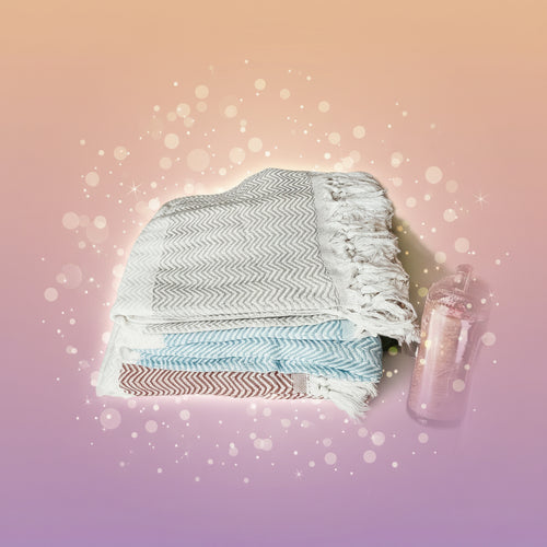 Stack of patterned towels on a marble surface with a metallic container.