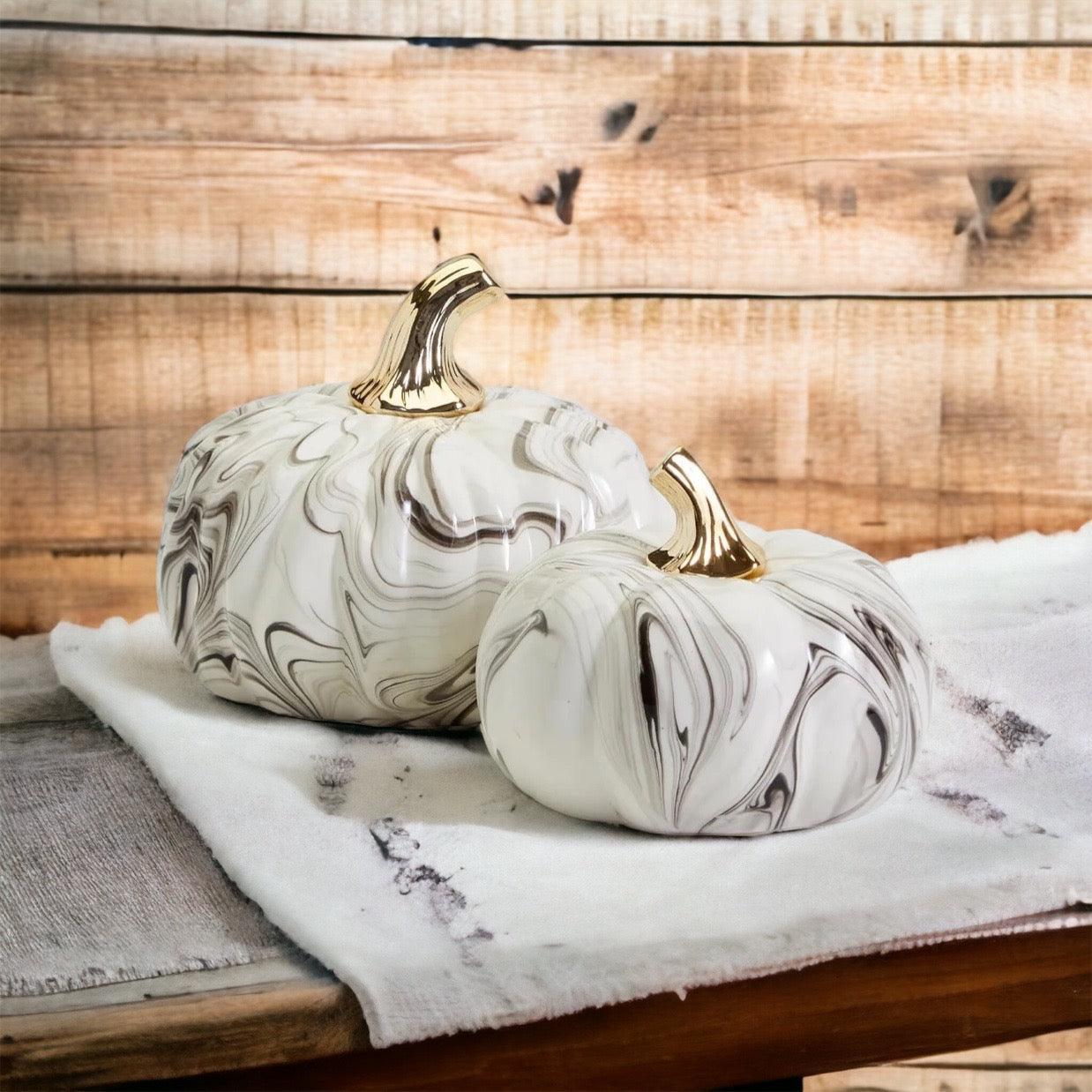 Two marble-patterned pumpkins with gold stems on a wooden surface.