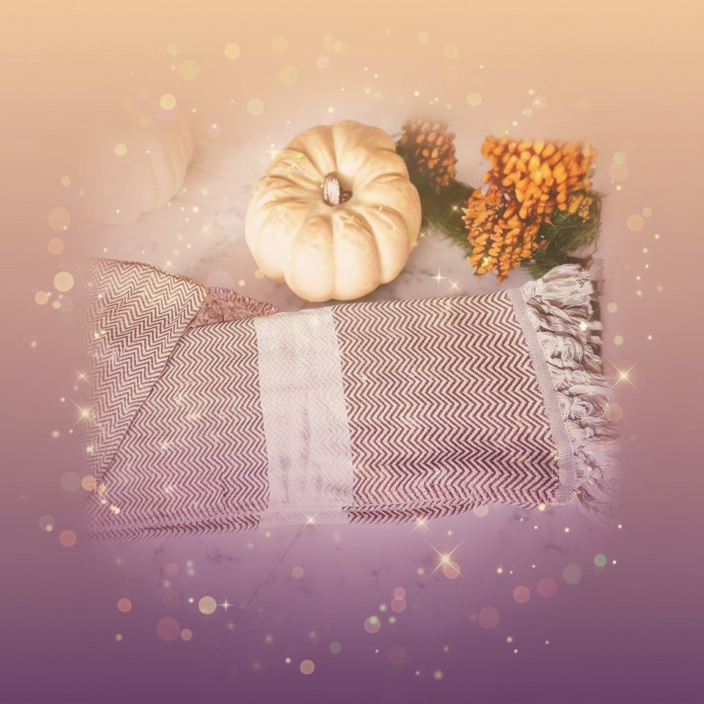 Decorative table runner with chevron pattern and tassels on a marble surface with pumpkins and foliage.
