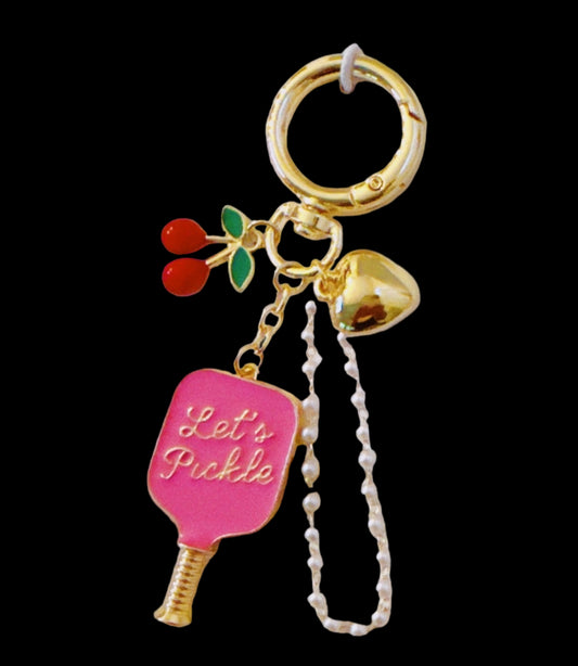 Two bag charms on their packaging with 'Let's Pickle' text on a beige background