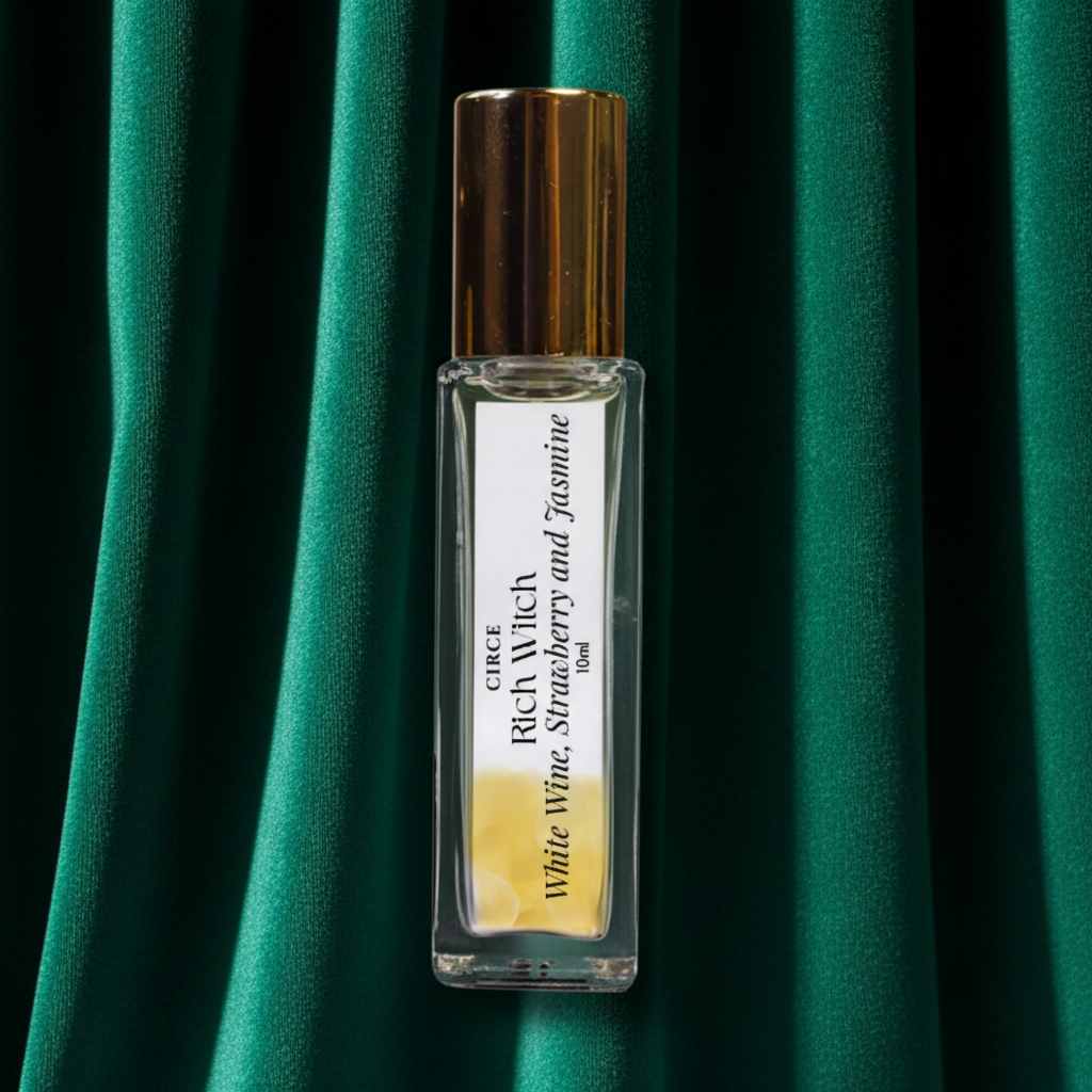 A clear glass roller bottle with a metallic gold cap, containing a pale yellow liquid. The bottle is labeled 'once RICHI White Wine, Strawberry and Jasmine Eau de Toilette'.