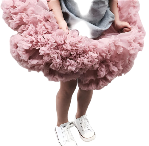 Child wearing a fluffy pink skirt and white sneakers on a gray surface