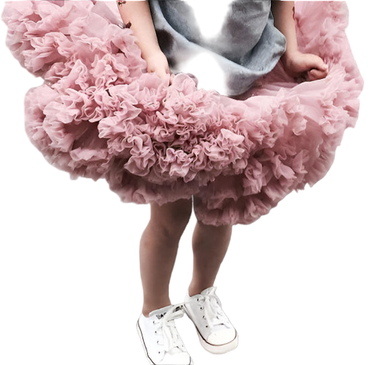 Child wearing a fluffy pink skirt and white sneakers on a gray surface