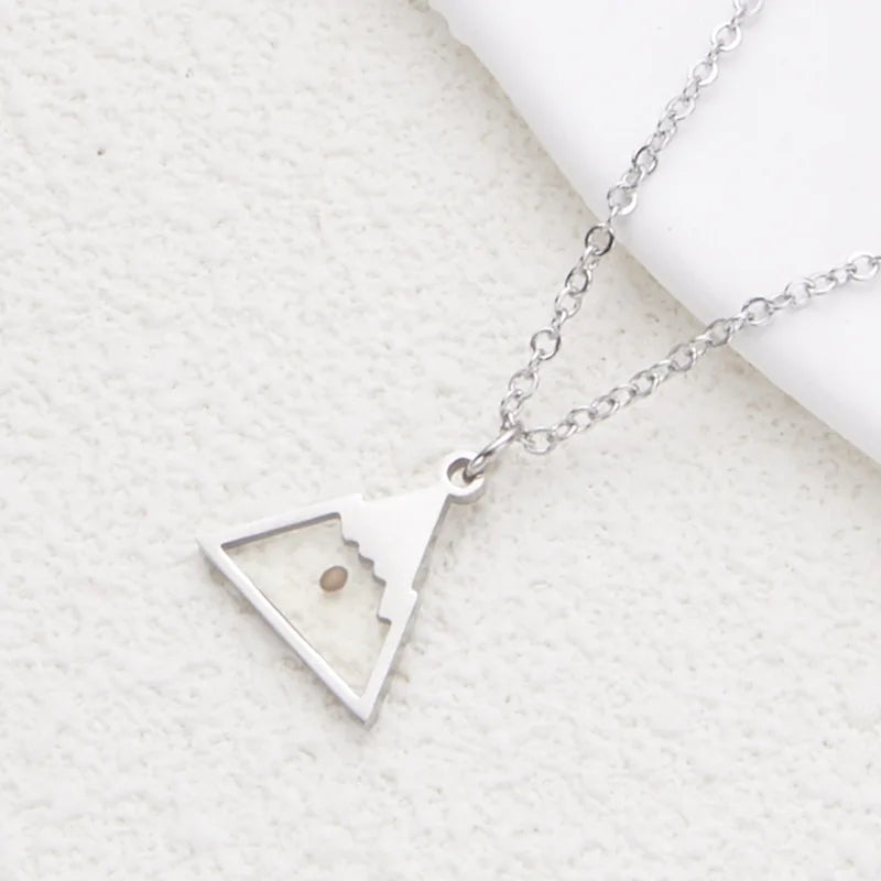 Silver necklace with a triangle pendant on a textured white surface