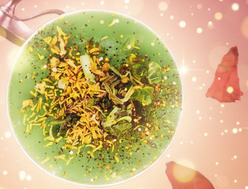 Green dish with yellow garnish on a decorative table with red flowers and a purple book.