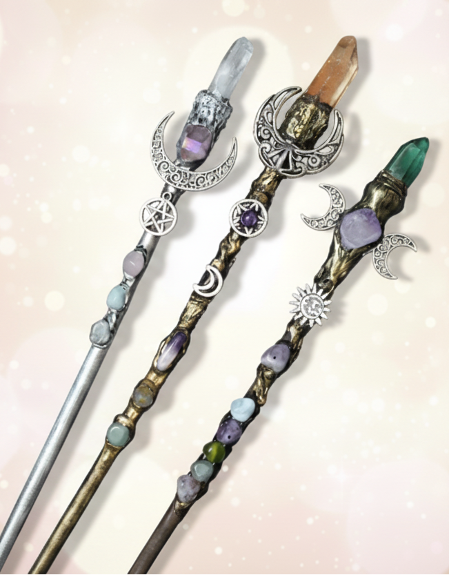 Decorative hair sticks with crystals and celestial designs on a dark surface.
