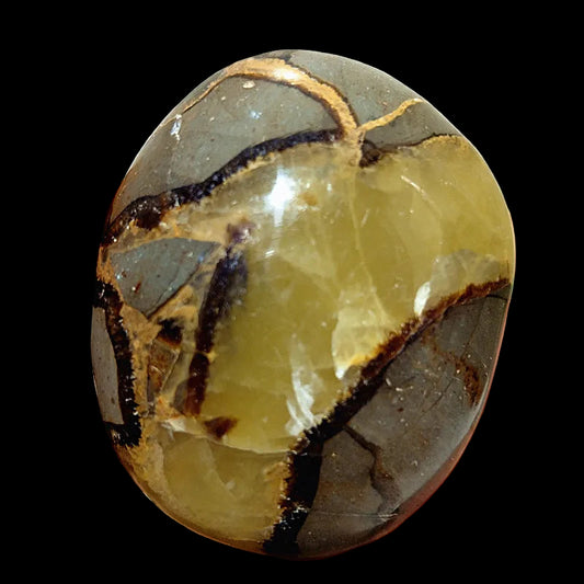 Hand holding a polished stone with natural patterns