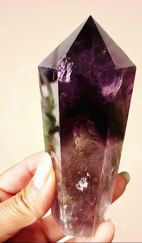 Amethyst crystal held in hand with green leaves in the background