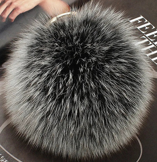 Furry pom-pom keychain on a dark surface with visible text