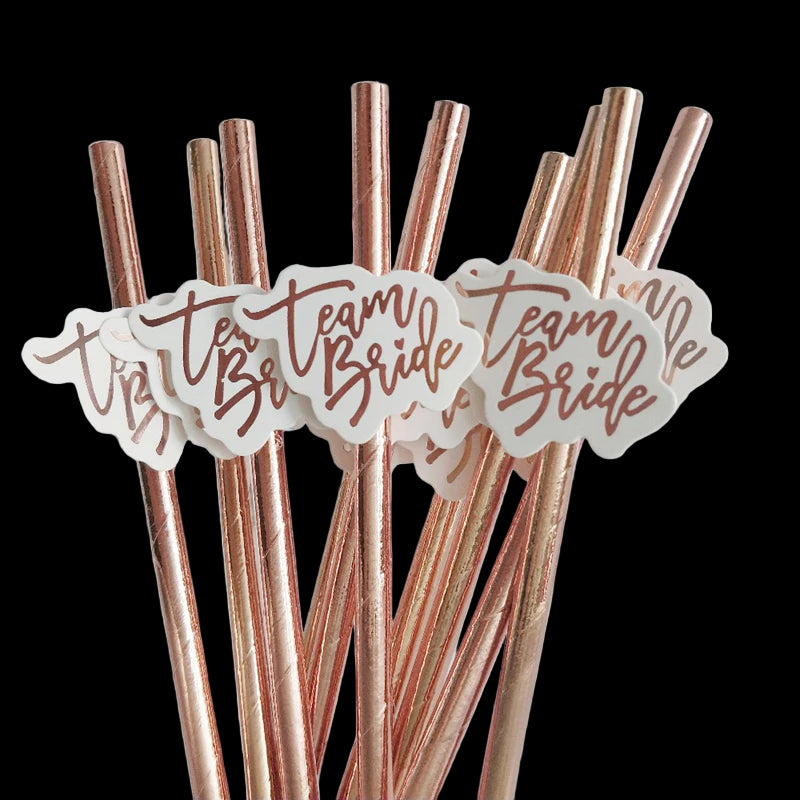 Rose gold straws with 'Team Bride' labels on a light gray background
