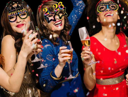 Three women celebrating New Year's Eve with party hats and glasses, surrounded by confetti.