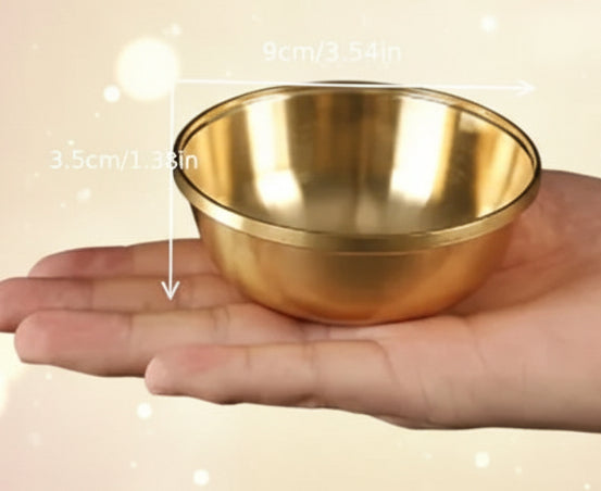 Gold bowl held in a hand with measurements indicated on a black background