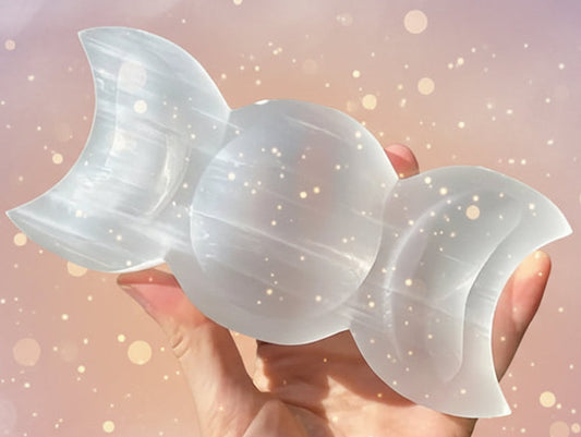 Hand holding a white stone sculpture with a natural outdoor background