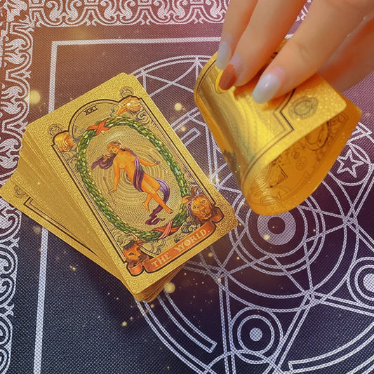 Gold playing cards with intricate designs on a black and white patterned surface