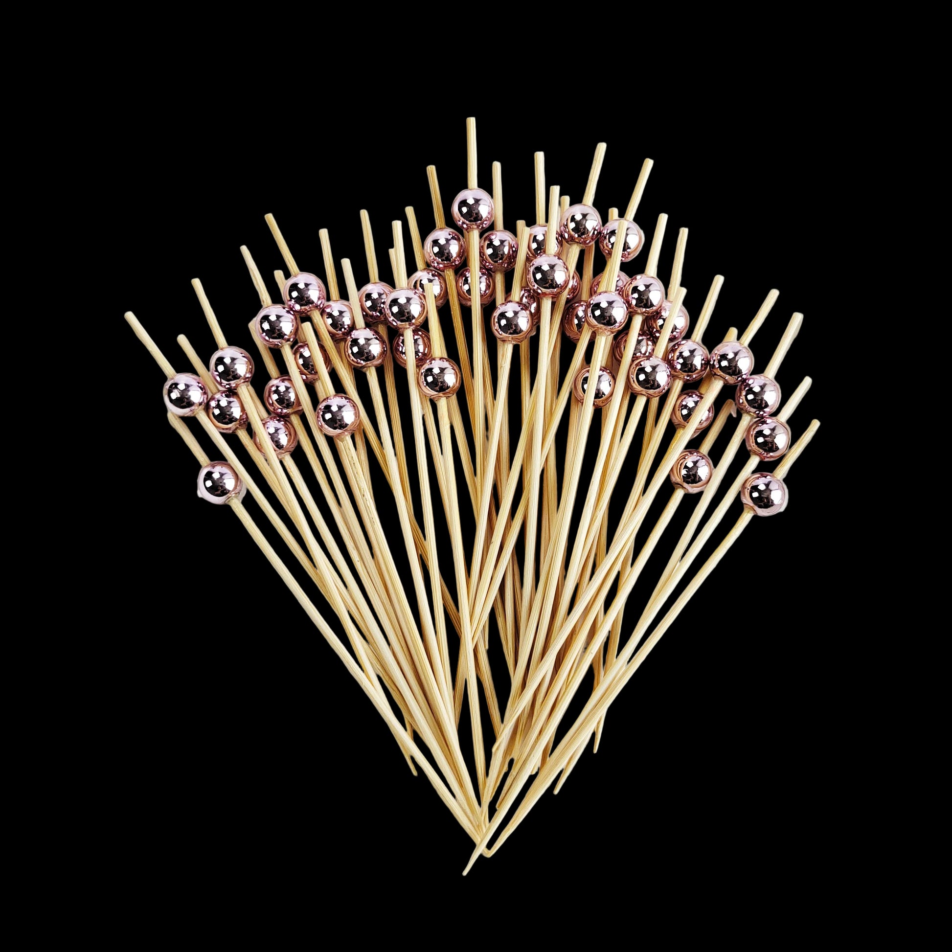 Bamboo skewers with rose gold beads on a white plate