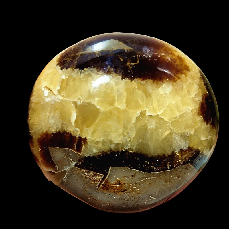 Close-up of a hand holding a polished crystal with brown and yellow patterns.