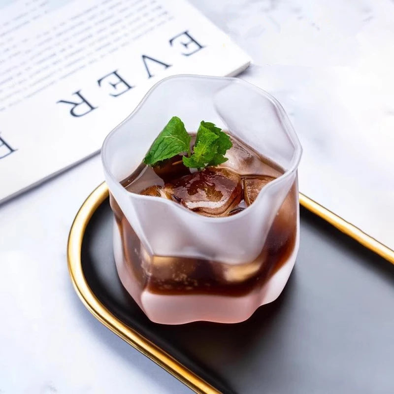 Iced drink in a decorative glass with mint leaves on a white surface