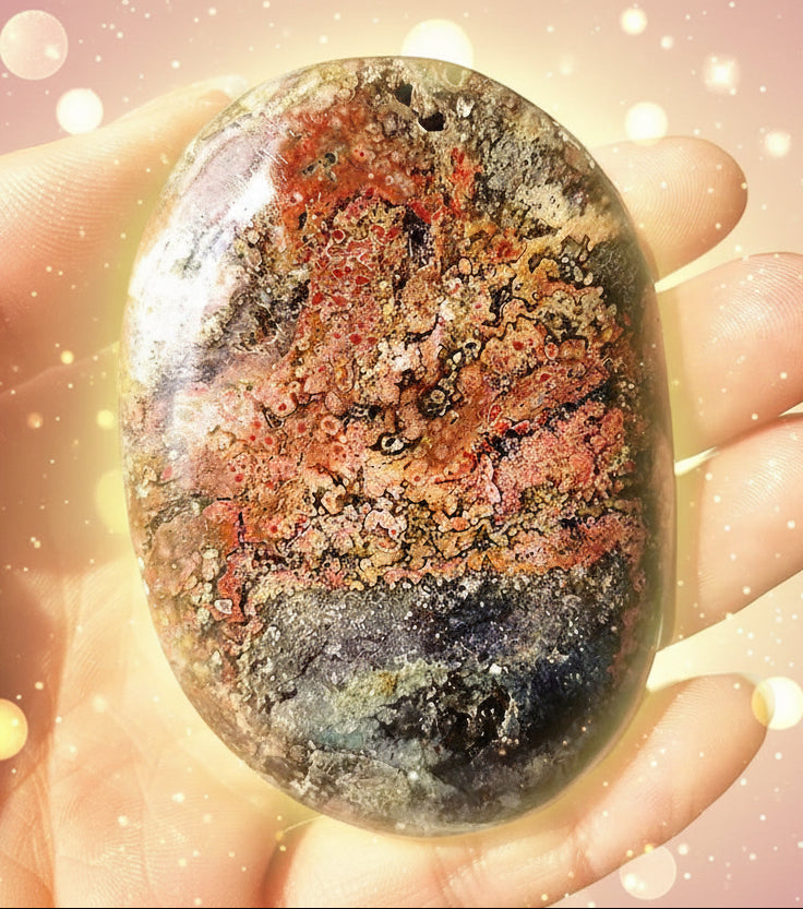Hand holding a multicolored stone with a blurred natural background
