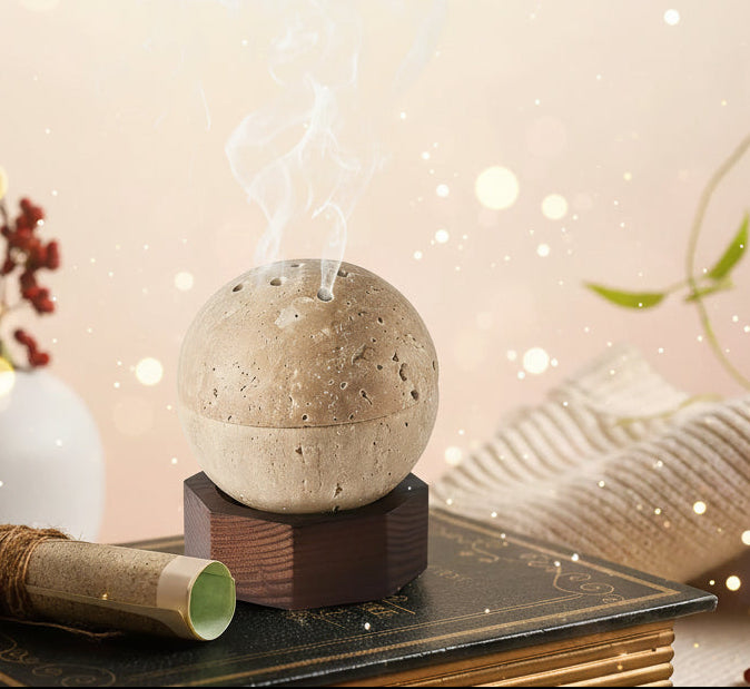 Stone-like diffuser emitting smoke on a dark background with books and plants.