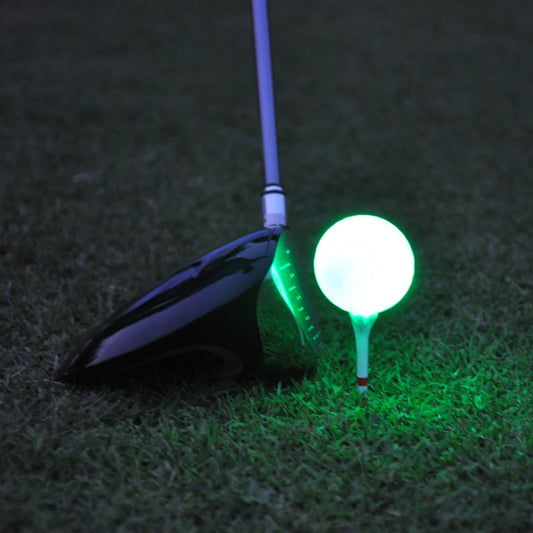Golf club and glowing green golf ball on grass at night