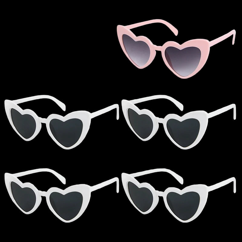 Set of heart-shaped sunglasses in pink, white, and black on a white background.